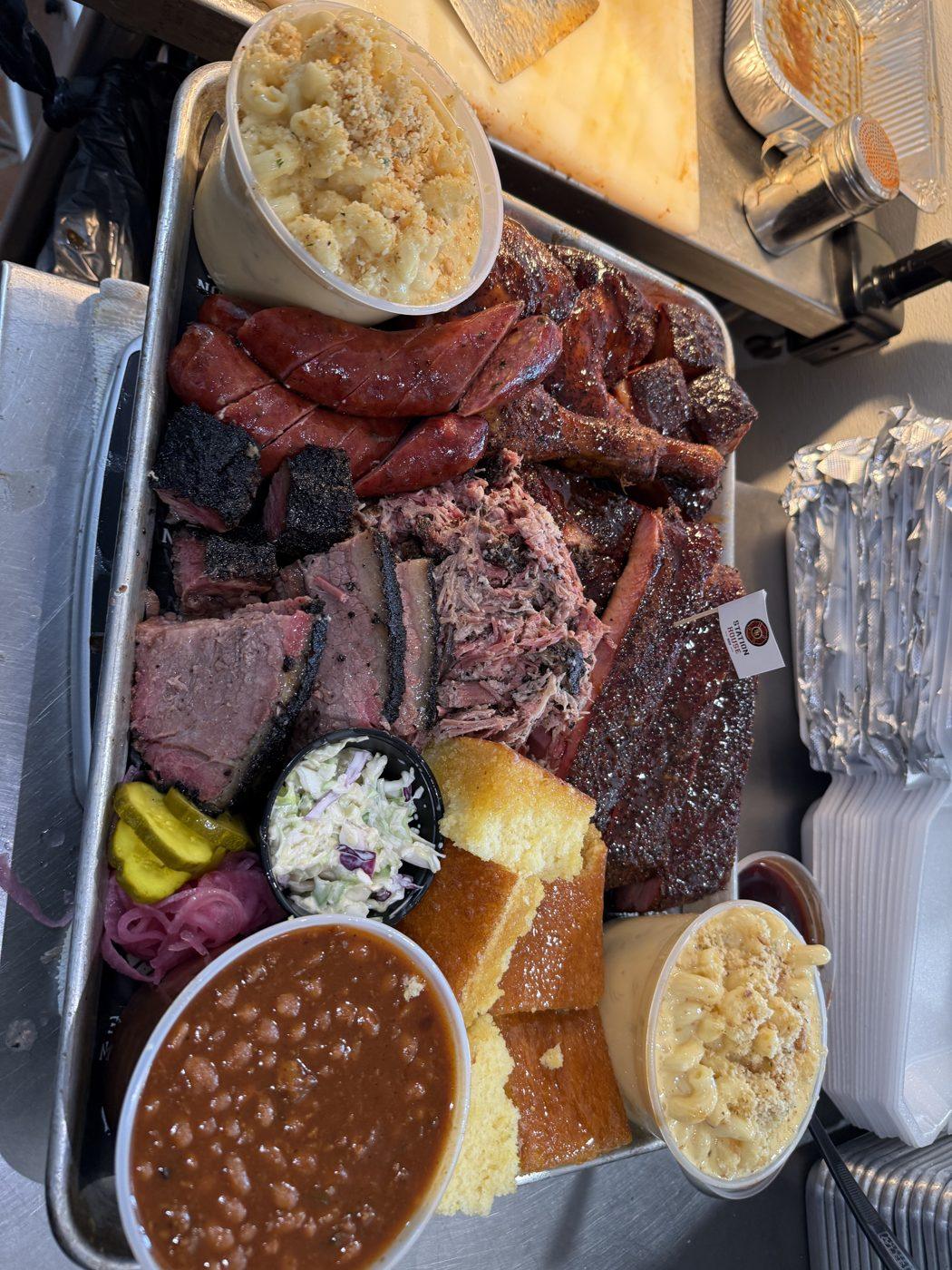 A family-style Station House BBQ spread with brisket, burnt ends, pulled pork, sausage, ribs, mac and cheese, Cowboy Baked Beans, coleslaw, and cornbread