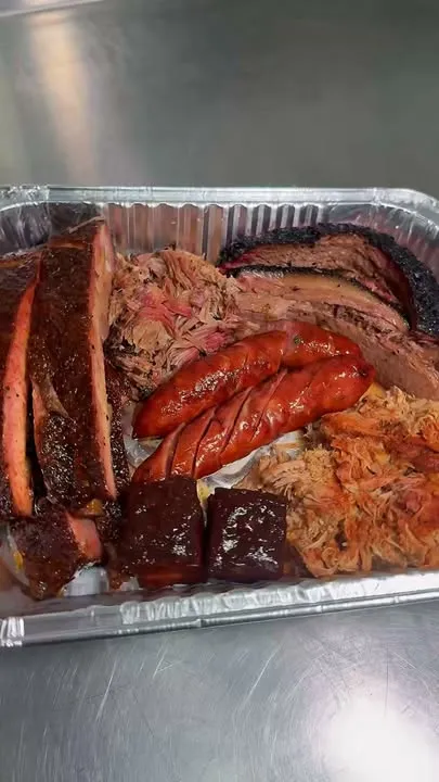A full foil pan of brisket, ribs, pulled pork, sausage and burnt ends
