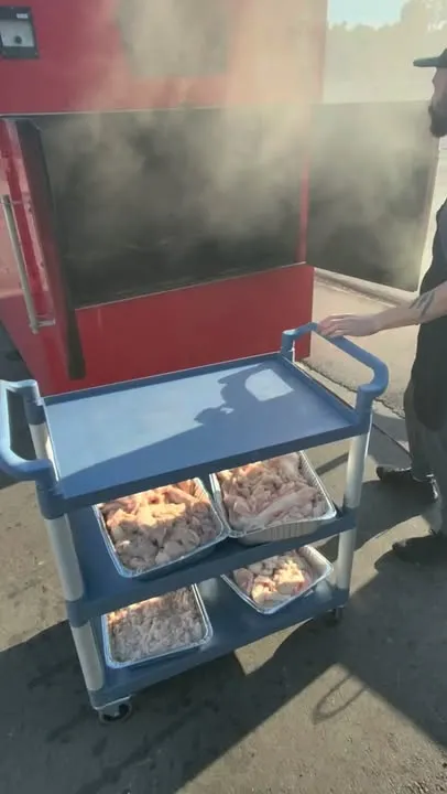 A cart of foil pans beside the smoker before a catering delivery