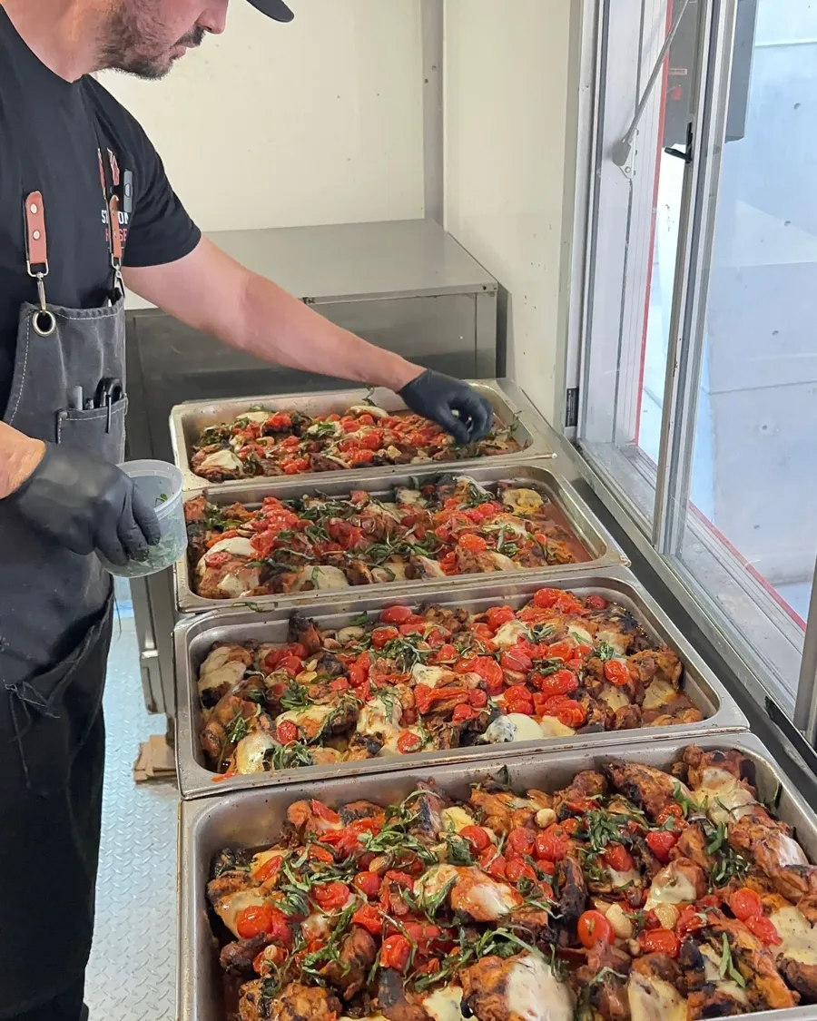 Four hotel pans of smoked chicken being finished for a catering order